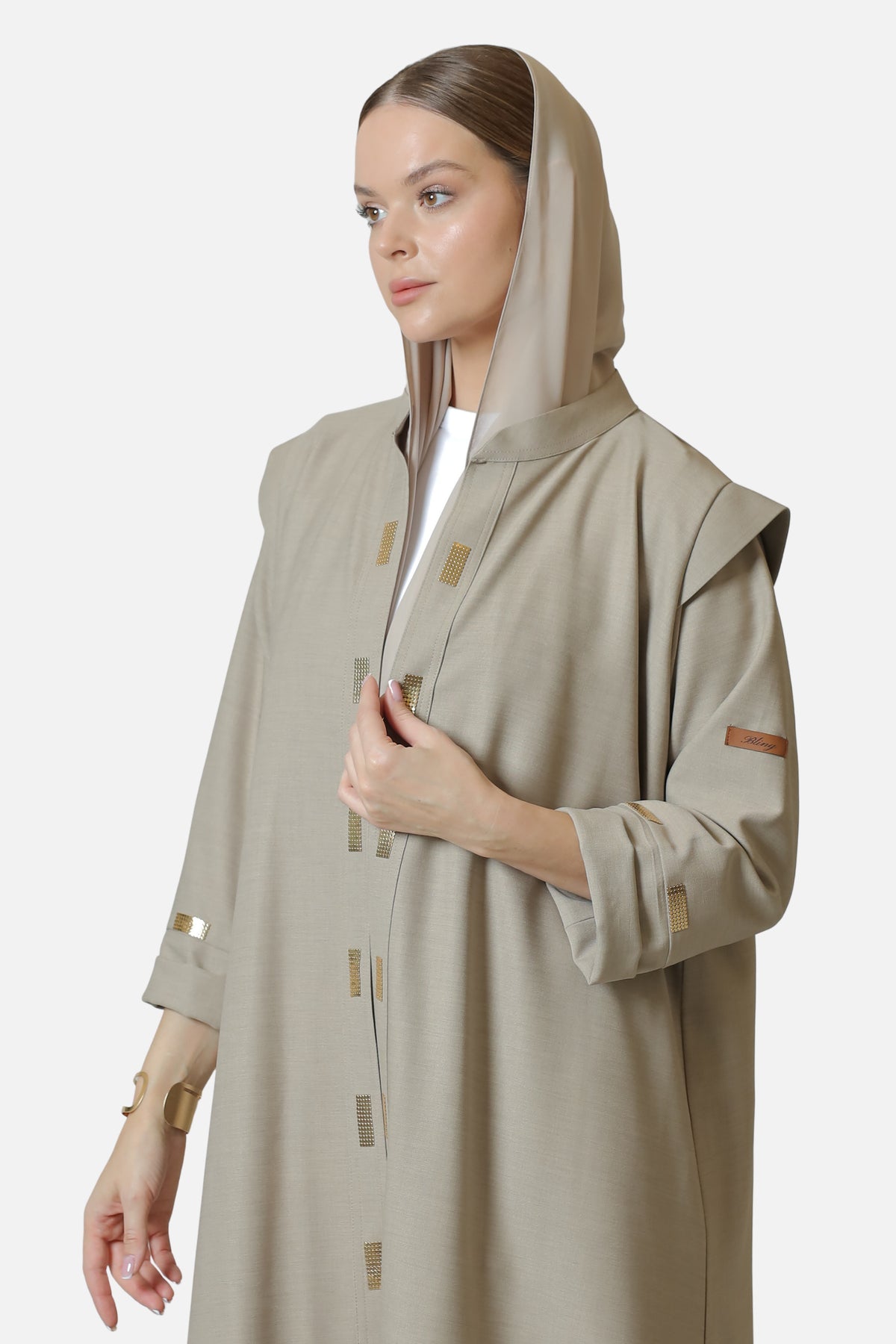 Beige cotton abaya with gold-tone details — three-quarter front view