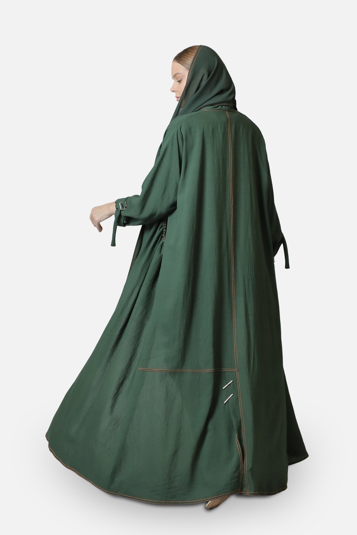 Side view of the green linen abaya showing its relaxed silhouette and contrast stitched edges.