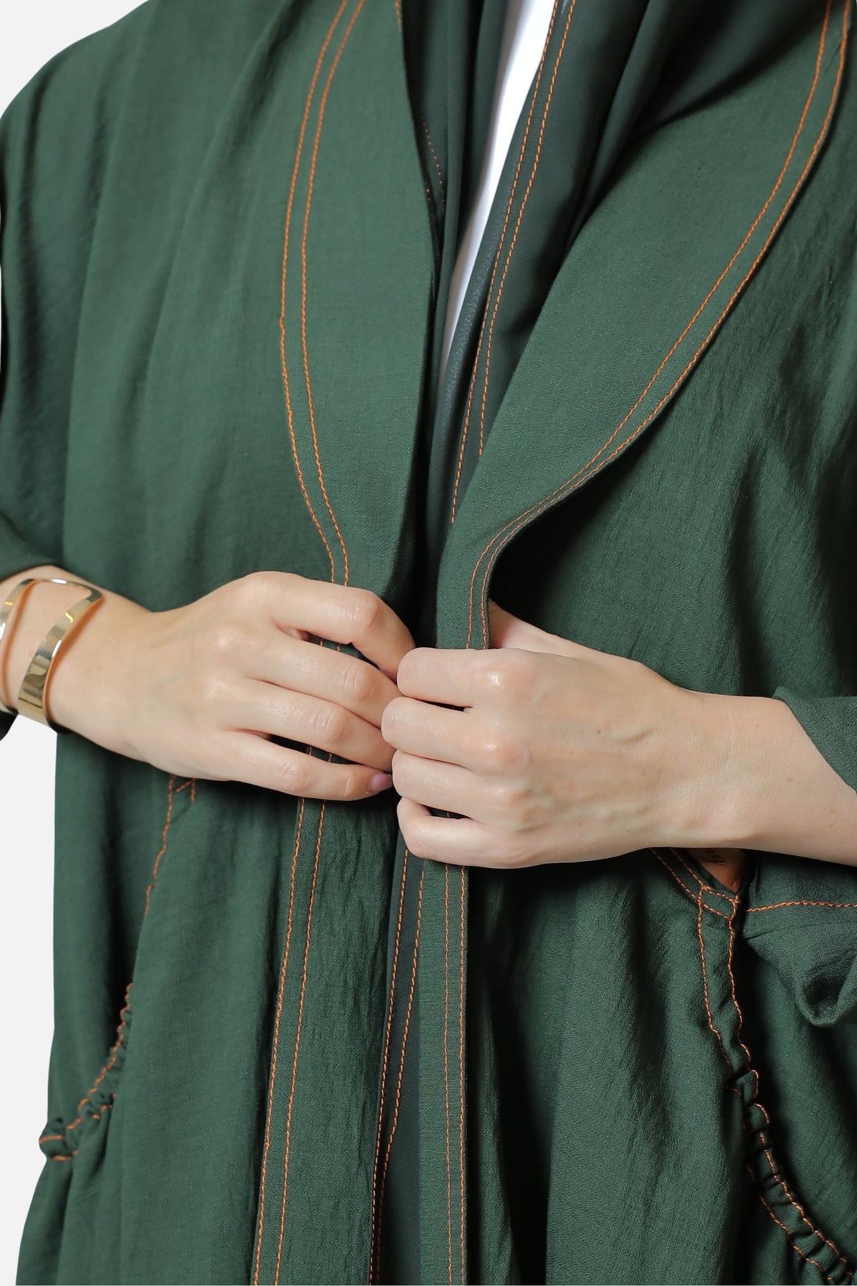 Close-up of the contrast stitching along the front edge of the green linen abaya.