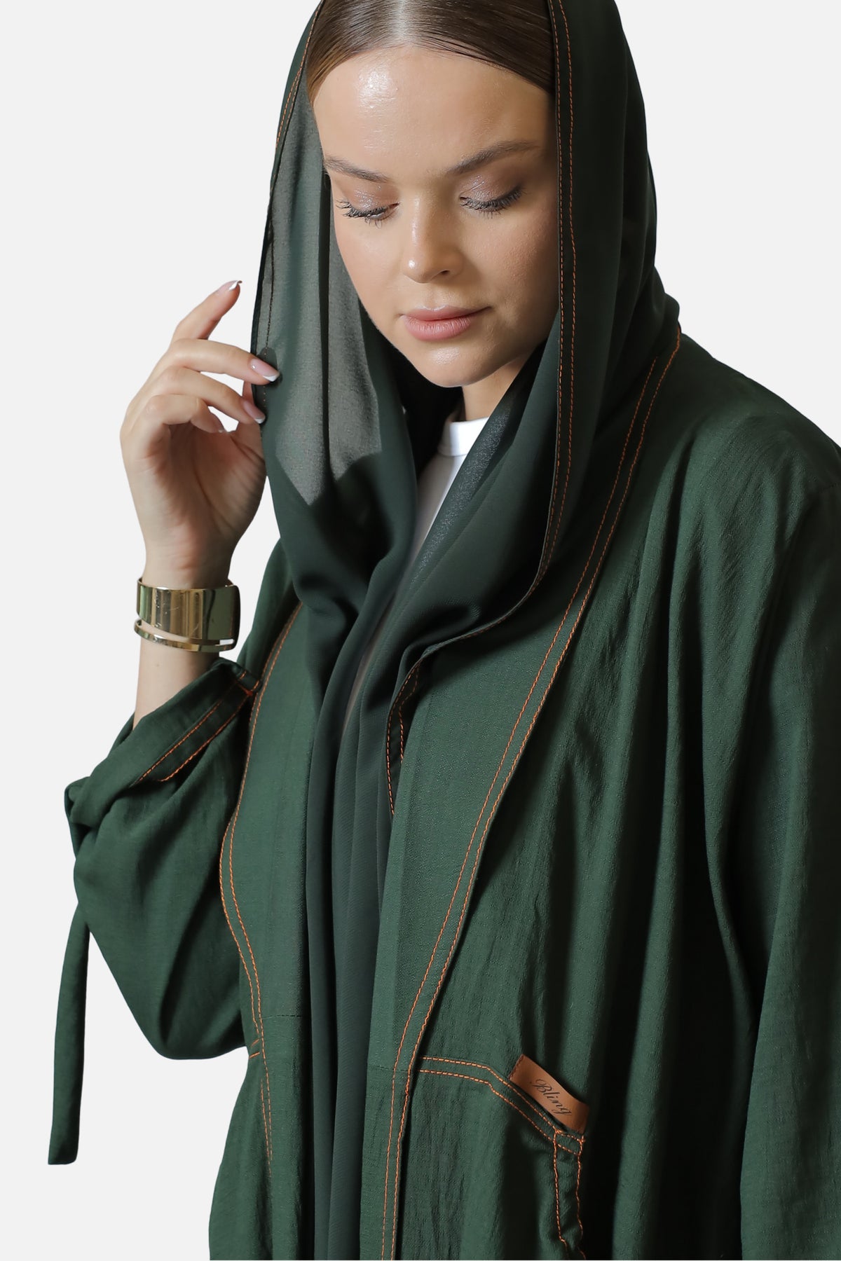 Detail of the green linen abaya's neckline and contrast stitched edge with the shaila.