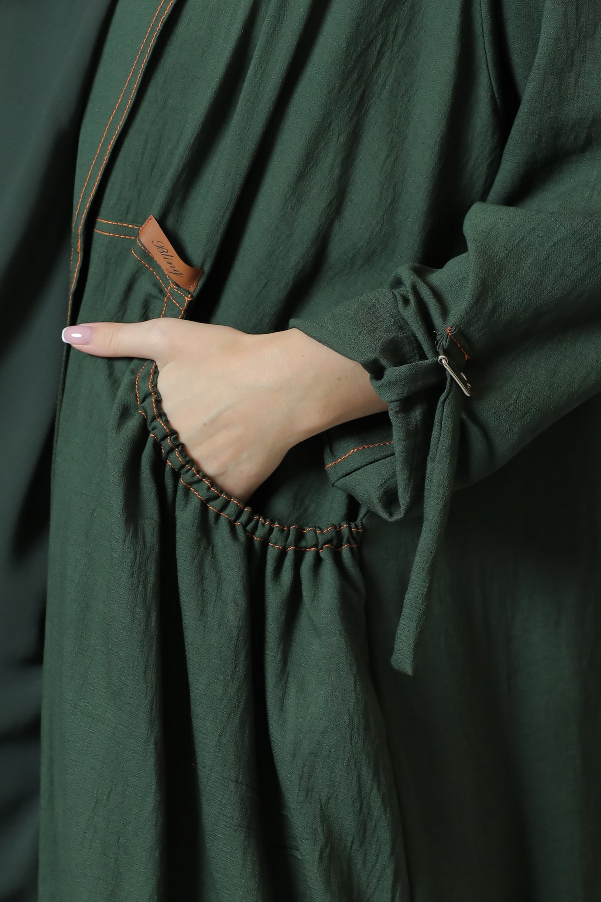Detail of the pocket and sleeve strap on the green linen abaya.