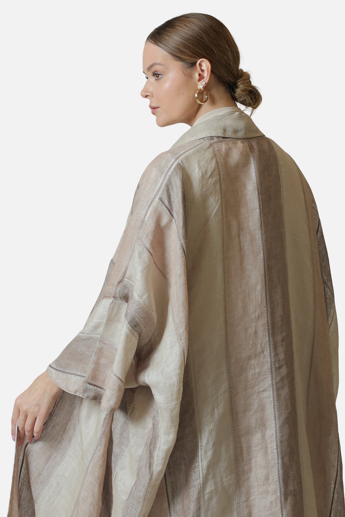 Rear three-quarter view of the neutral striped linen abaya.