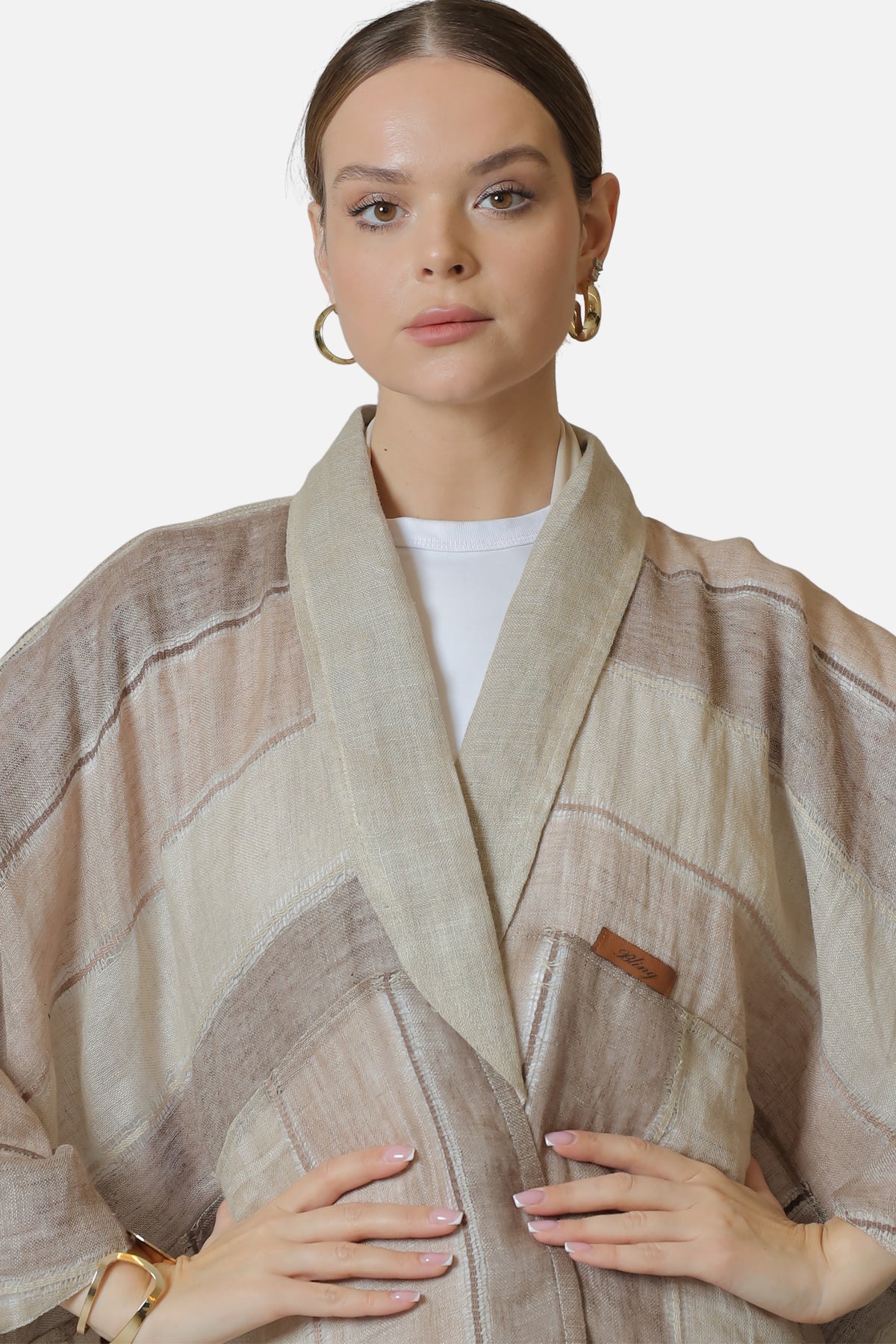 Close view of the neutral striped abaya’s neckline, fabric texture and Bling label.
