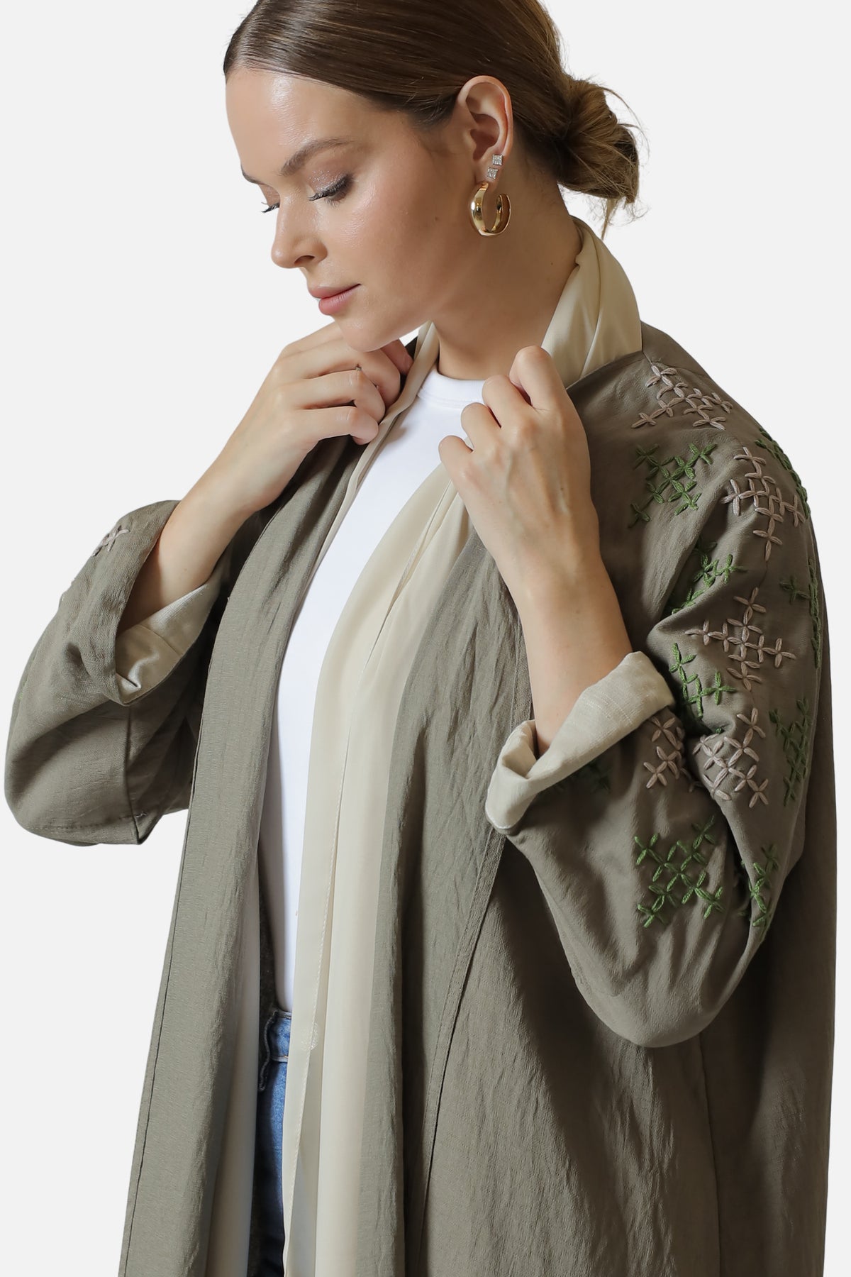 Close-up of the light green sleeve embroidery and contrasting cuff on the beige linen abaya.