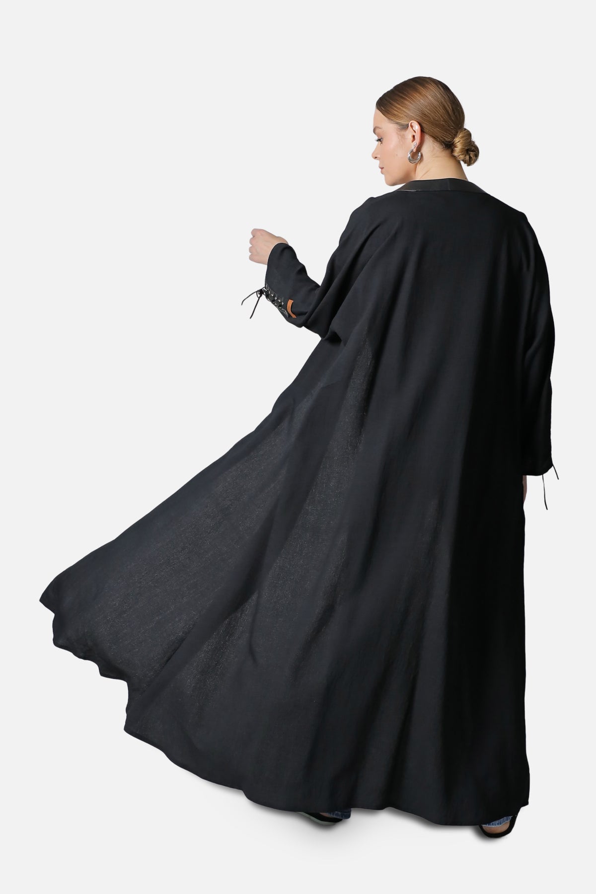 Black linen abaya in movement, back view with the hem flaring