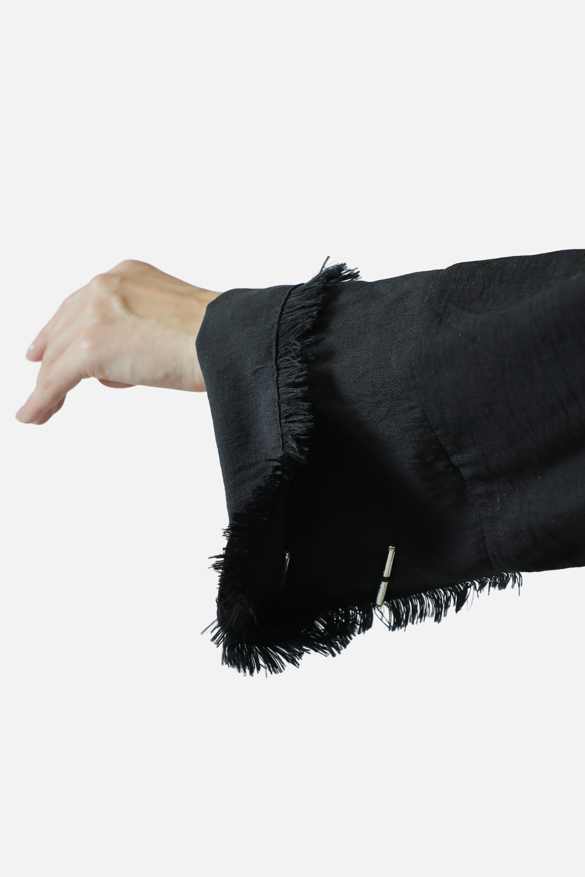 Fringed cuff edge on the black linen abaya sleeve, detail view