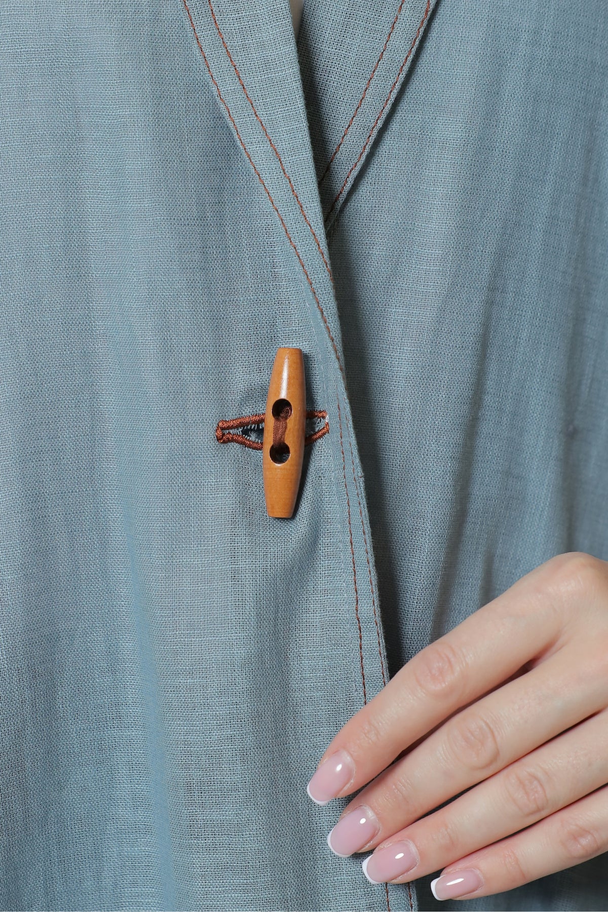 Close-up of the wooden front toggle and textured blue-gray linen fabric.
