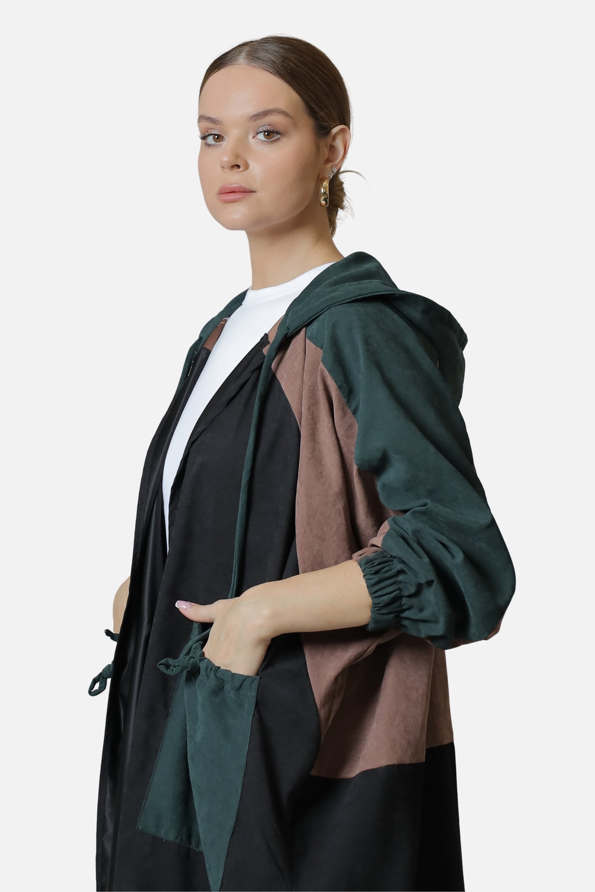 Dark green suede abaya with contrasting brown and black panels, worn open with a hand in the front pocket.
