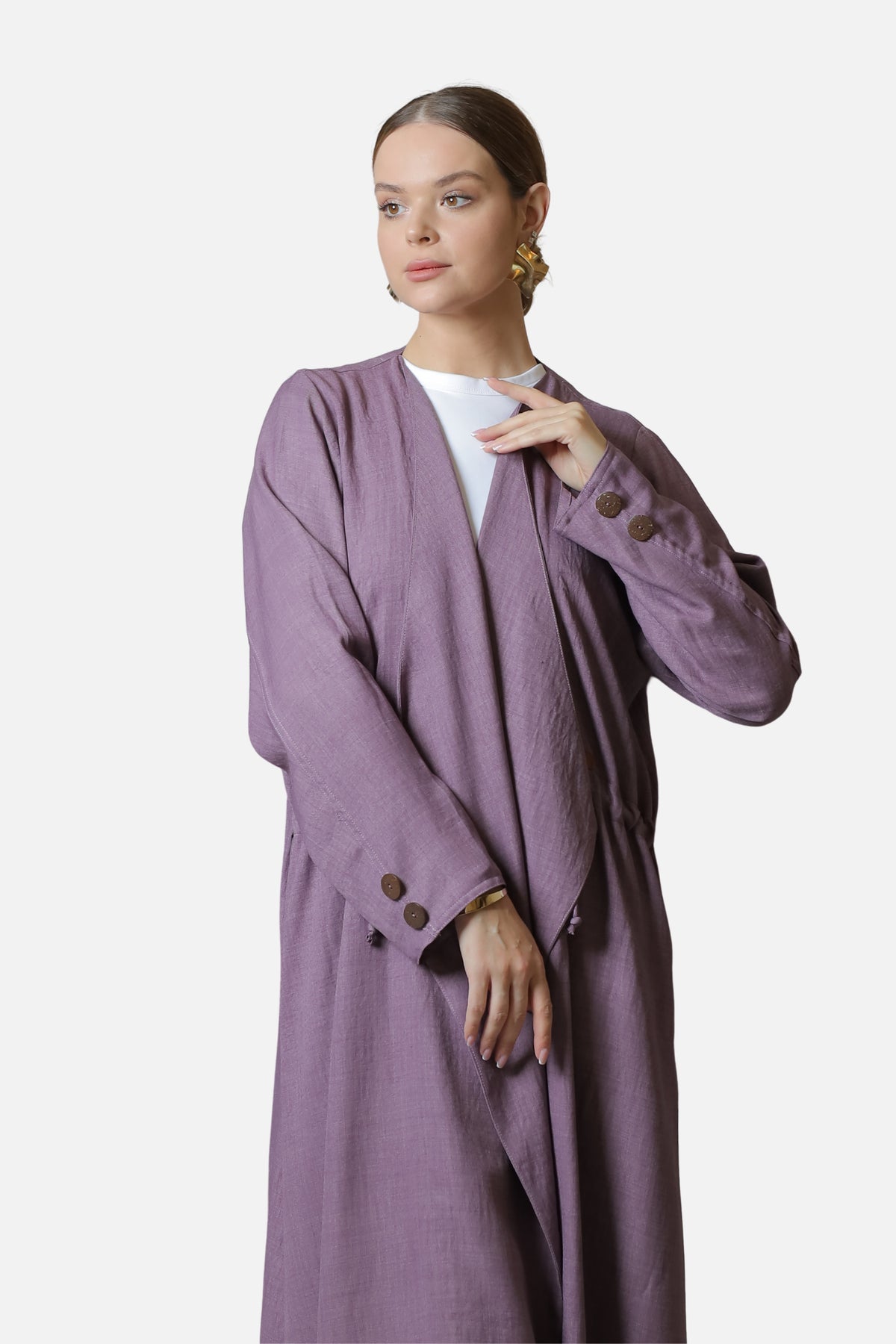 Purple cotton abaya with sleeve button details, shown in an editorial pose with one hand raised.