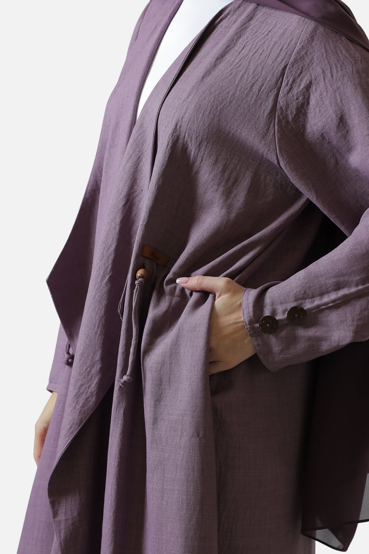 Detail of the purple abaya’s side pocket, Bling label, cord detail, and sleeve buttons.