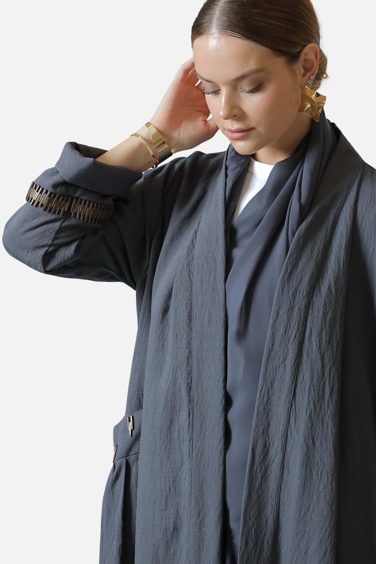 Close view of the gray abaya's textured fabric and gold-tone sleeve decoration.