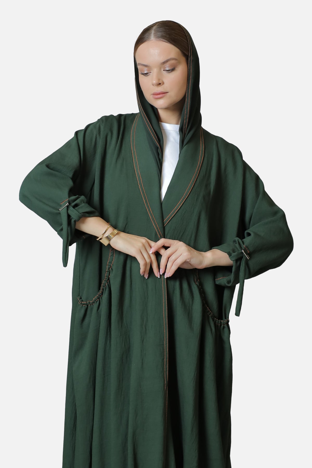 Green linen abaya with contrast stitch details, worn with the shaila draped over the head.