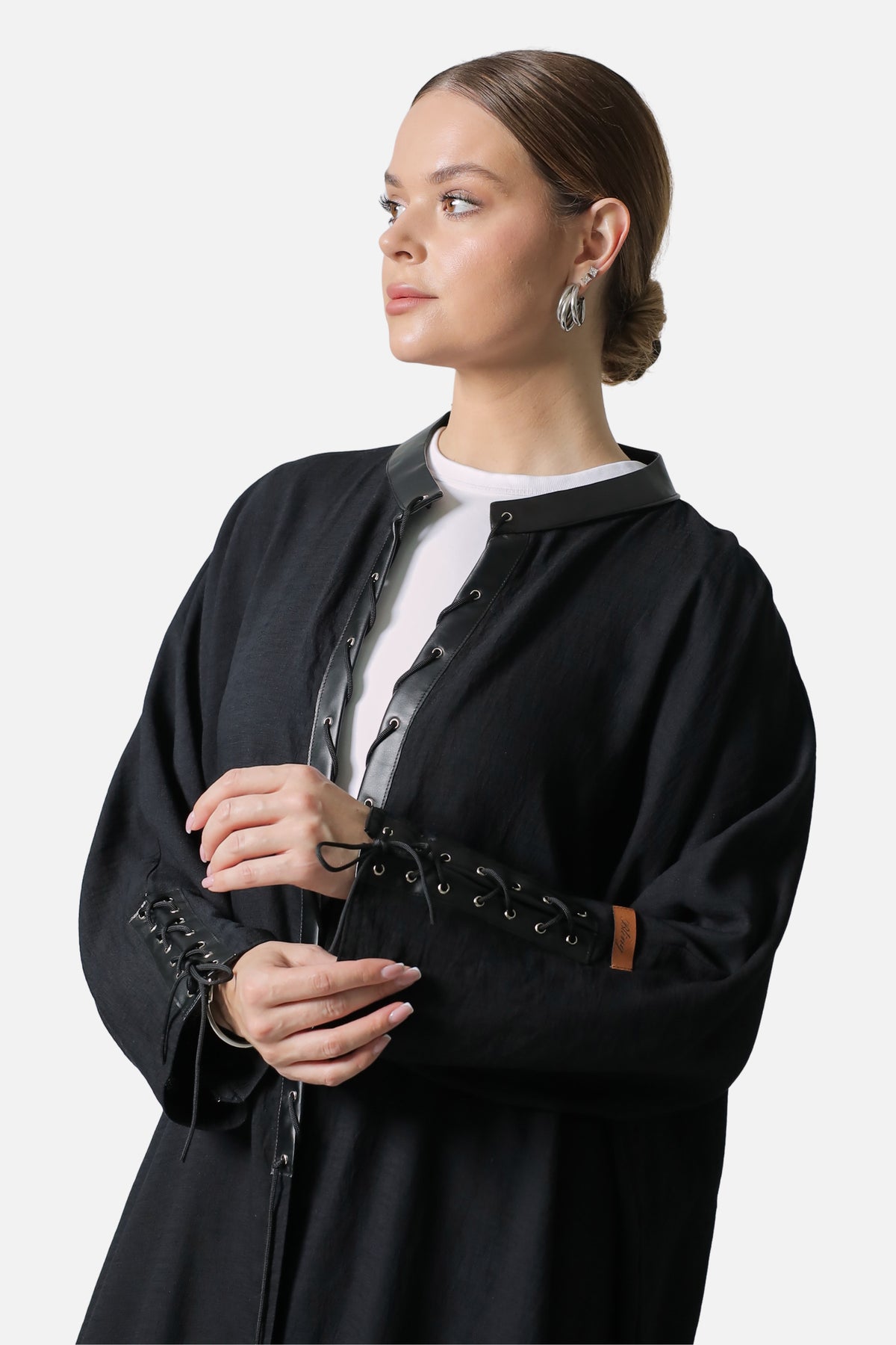 Black linen abaya, three-quarter view showing the leather placket and laced cuff