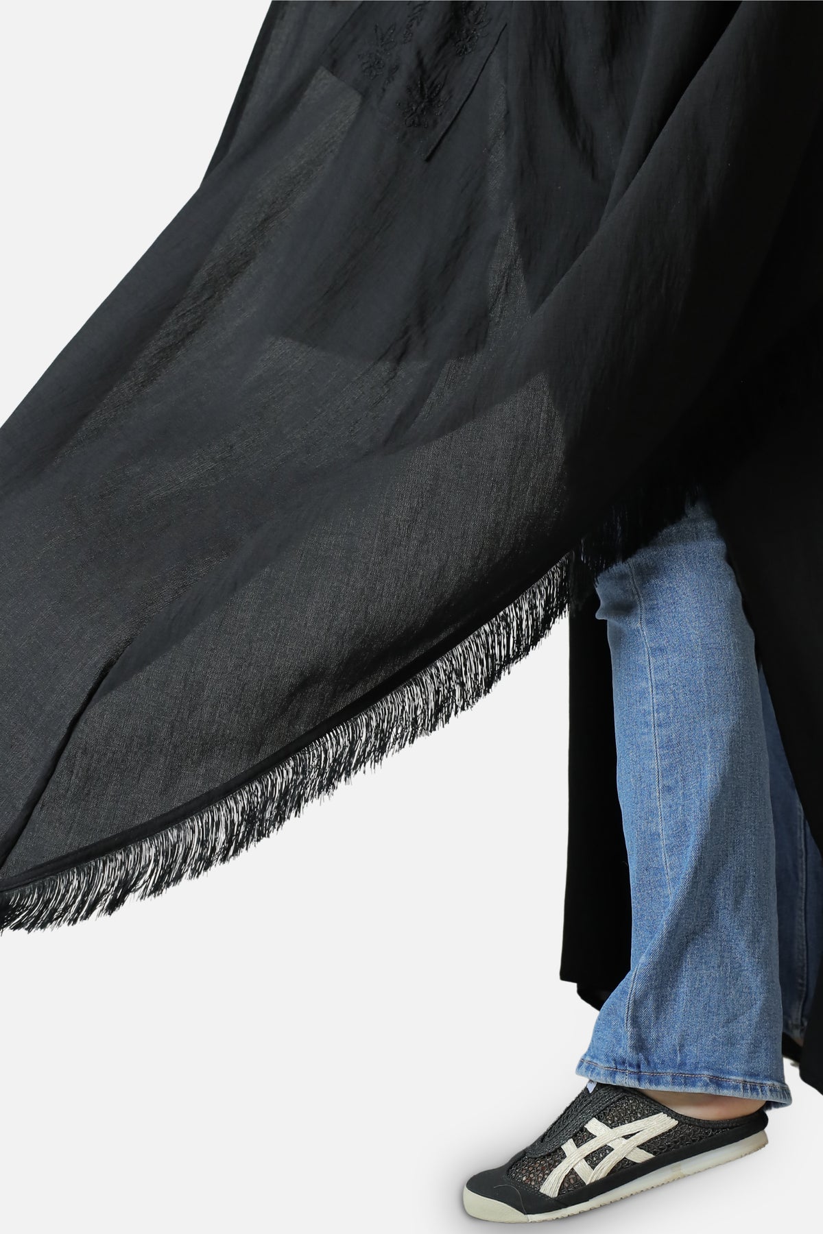 Fringed hem of the black linen abaya in movement, close-up