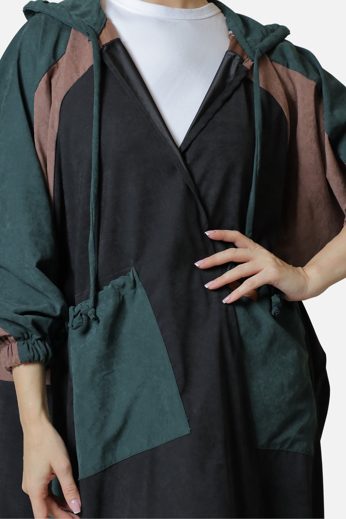 Close-up of the dark green suede abaya's front pocket and contrasting panel detail.