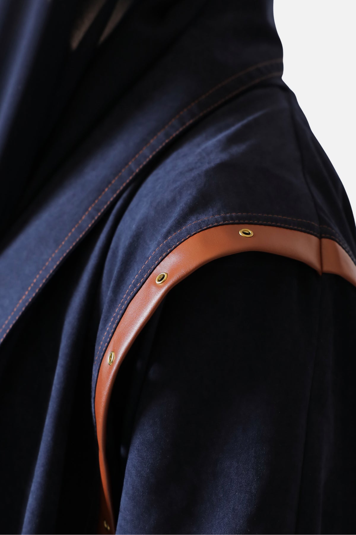 Leather trim and metal studs along the shoulder seam of the suede abaya, close-up detail